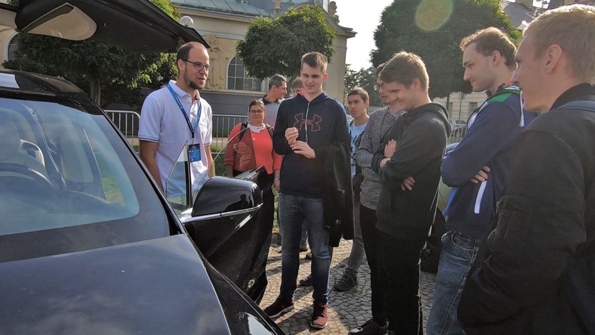 Corporate event guests by a Tesla with open doors