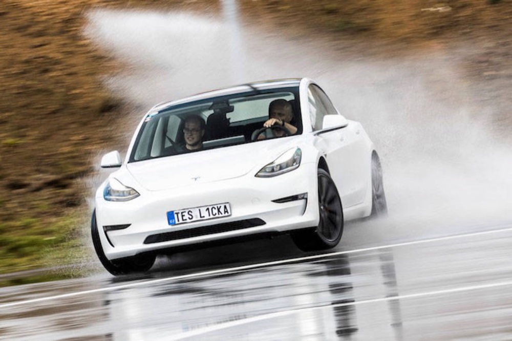 White Tesla Model 3 drifting on a wet track